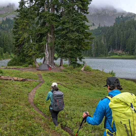 Wanderer nähern sich mit ihren Ultraleicht MSR® FreeLite™ 2 V2 Zelten aus Micromesh-Zeltmaterial einem Campingplatz an einem Bergsee.