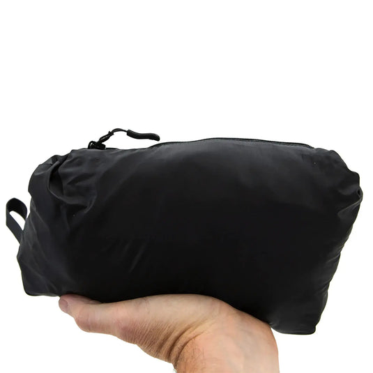 Eine Hand hält eine schwarze Tasche mit Reißverschluss vor weißem Hintergrund, mit Carinthia® Techno Stretch-Einsätzen.