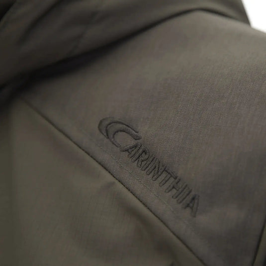 Nahaufnahme eines grauen Stoffes mit gesticktem „Carinthia“-Logo auf einer Carinthia® MIG 4.0 Jacke.