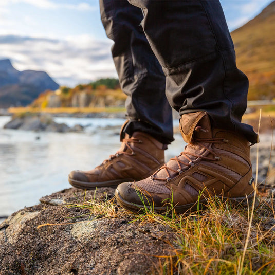 Eine Person mit wasserdichten und atmungsaktiven Wanderschuhen HAIX® BLACK EAGLE® ATHLETIC 2.0 N GTX steht bei Sonnenuntergang an einem Bergsee.