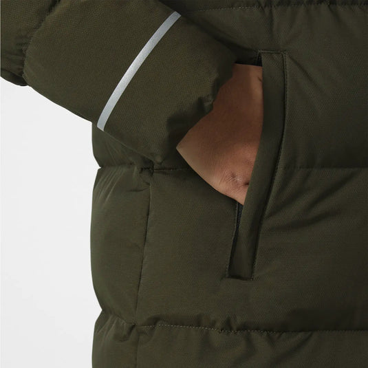 Nahaufnahme eines grünen Adore Puffy Parka von Helly Hansen Juniors mit einer Reißverschlusstasche und einem reflektierenden Streifen am Ärmel.