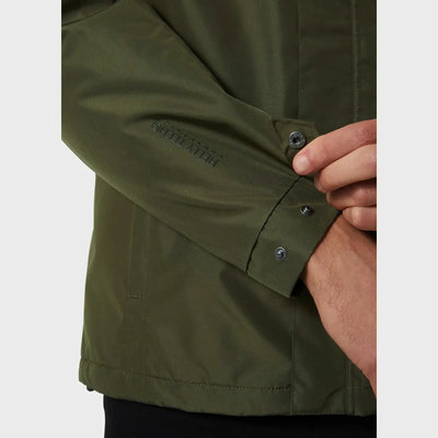 Nahaufnahme des Arms einer Person mit der Manschette einer grünen, isolierten, wasserdichten Dubliner-Herrenjacke von Helly Hansen® mit Knopfdetails.