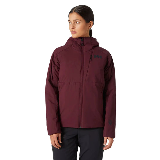 Frau trägt eine helly Hansen® Women's Odin Stretch Hood Isolator 2.0 kastanienbraune Jacke mit Kapuze, Frontreißverschluss und Seitentaschen.