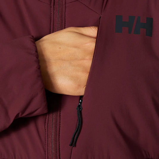 Eine Hand, die aus einer geöffneten burgunderroten Jacke herausragt, mit einem sichtbaren „Helly Hansen® Women's Odin Stretch Hood insulator 2.0“-Logo.