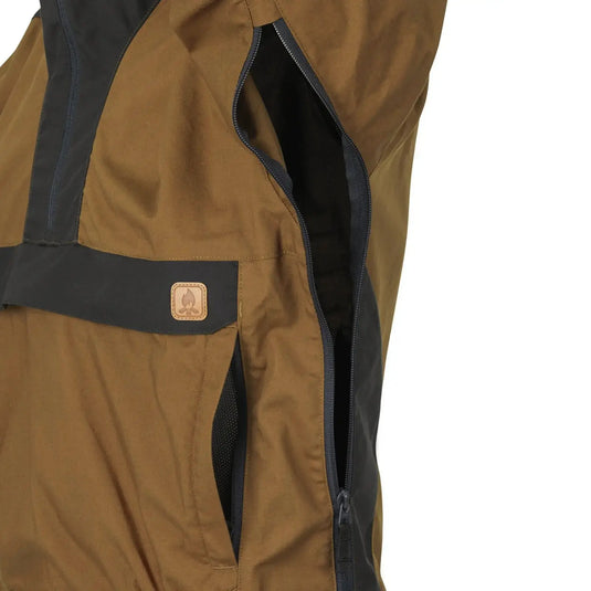 Nahaufnahme der Seitentasche und des Reißverschlussdetails einer braunen Helikon-Tex® Woodsman Anorak Jacket® für den Außenbereich mit einem Markenlogo-Aufnäher.