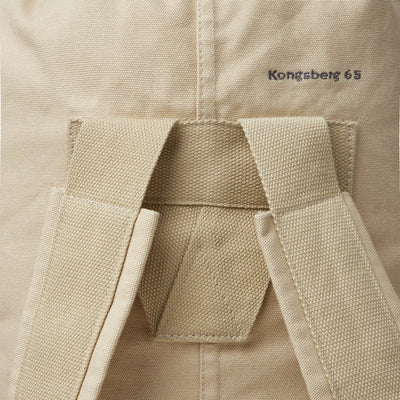 Nahaufnahme eines beigen Nordisk® Kongsberg 65, Duffle Rucksack mit Gürtelschlaufe und gesticktem Text „Nordisk“.