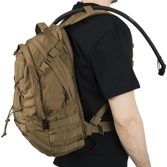 Person, die einen braunen Helikon-Tex® EDC Rucksack – Cordura (21 Liter) taktischen Rucksack über einer Schulter trägt.