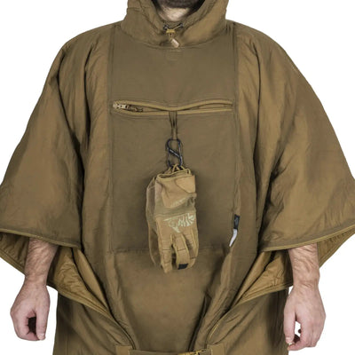 Person in einem braunen Helikon-Tex® Swagman Roll Poncho, der einen Handschuh hält.