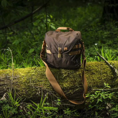 Eine Helikon-Tex® Bushcraft Haversack Bag – Cordura, die auf einem moosbedeckten Baumstamm in einer Waldumgebung ruht.