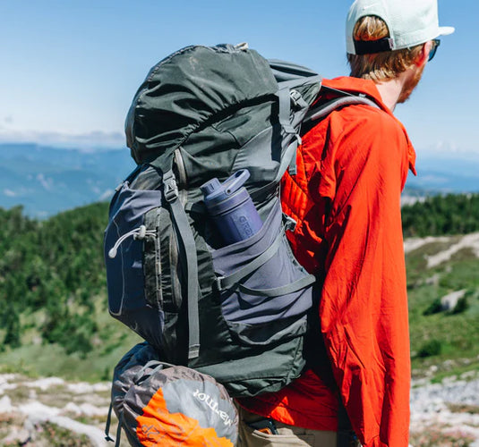 Ein Wanderer mit einem großen Rucksack blickt auf Berge.