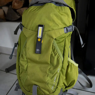 Ein grüner Rucksack mit einer Brennenstuhl® LED Akku Handlampe PL 200 A an einem seiner Riemen, flexibel einsetzbar.