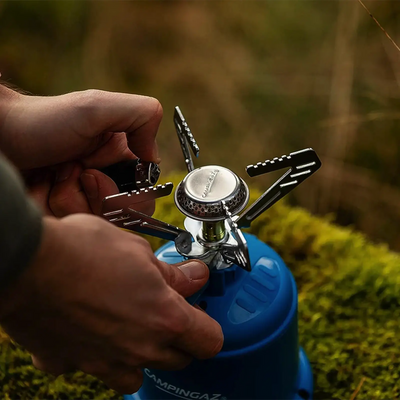 Eine Person zündet im Freien einen Campingaz® Micro Plus 1250W Kocher an.