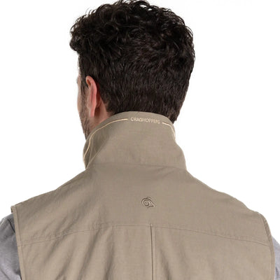 Rückansicht einer Person mit lockigem Haar, die eine beige Craghoppers NosiLife Adventure Gilet IV für Herren Jacke mit Insektenschutz und Markenlogo am Kragen trägt.