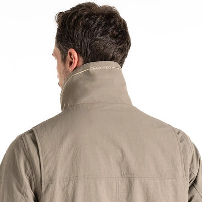 Mann trägt eine beige Craghoppers NosiLife Adventure Jacket IV für Herren mit dem Markennamen „Craghoppers“ am Kragen.