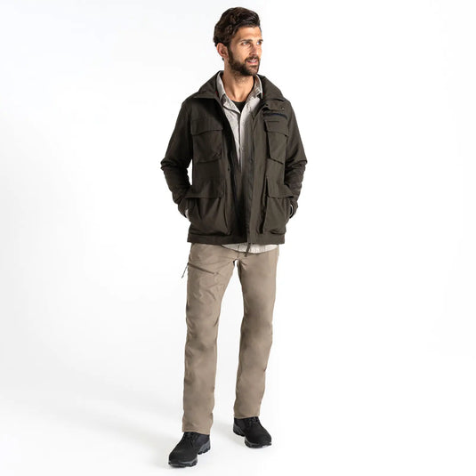 Mann steht in lässiger Pose und trägt eine Craghoppers NosiLife Adventure Jacke IV für Herren, beige Hosen und schwarze Schuhe auf weißem Hintergrund.