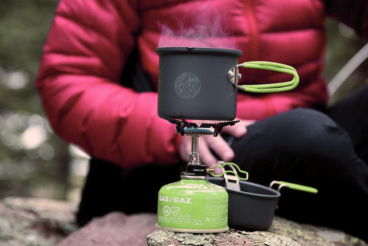 Portable Gaskocher mit Topf, Outdoor, Camping, Kochen, Person unkenntlich.