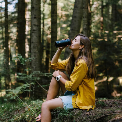 Frau trinkt im Wald aus einem Esbit® Thermobecher mit Klick-Verschluss 450ml.