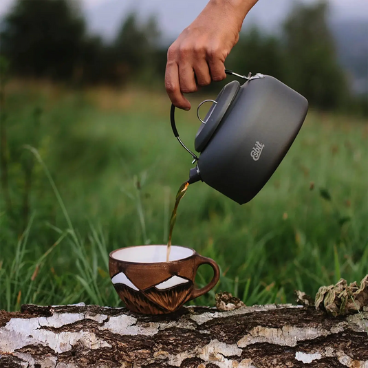 Tee aus einem Esbit® Wasserkessel Aluminium 600ml in eine Tasse im Freien gießen.