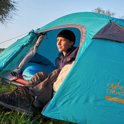 Mann sitzt in einem Zelt auf einem Campingplatz in warmen Nächten mit dem Grand Canyon® Fairbanks 190 - Schlafsack.