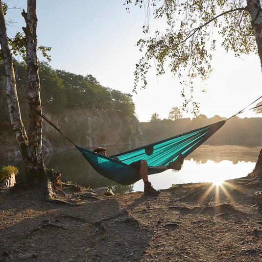 Person entspannt sich bei Sonnenuntergang in einer Grand Canyon® Bass Hammock Double am Seeufer.