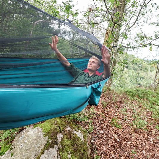 Mann entspannt sich in einer Grand Canyon® Bass Mosquito-Hängematte im Wald.