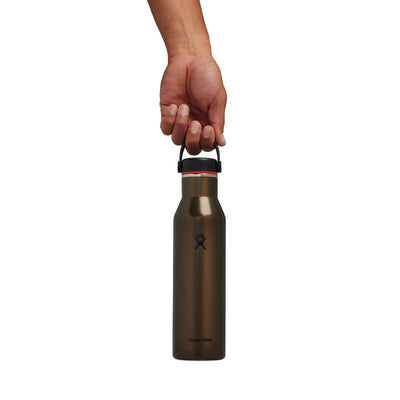 Eine Person hält eine leichte Hydro Flask® 21 oz (621 ml) Lightweight Standard Mouth Trail Series™ Wasserflasche am Hals vor einem neutralen Hintergrund.