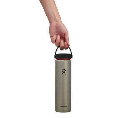 Eine Hand hält eine Hydro Flask® 24 oz (710 ml) leichte Wide Mouth Trail Series™ Edelstahl-Wasserflasche mit schwarzem Deckel und Griff.