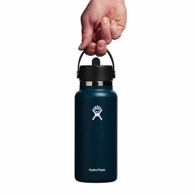 Eine Hand hält eine marineblaue Hydro Flask® 32 oz (946 ml) Wide Mouth mit Flex Straw Cap-Wasserflasche am Griff.