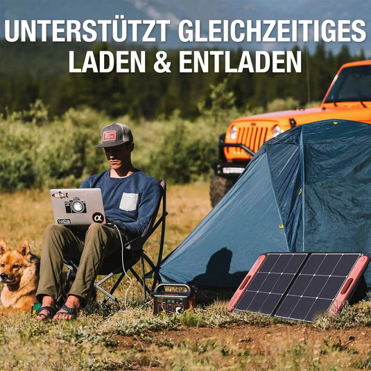 Ein Mensch sitzt mit einem Laptop neben einem Zelt im Freien, während ein Hund daneben liegt; Eine tragbare Jackery Explorer 240 Power Station ist im Vordergrund sichtbar.