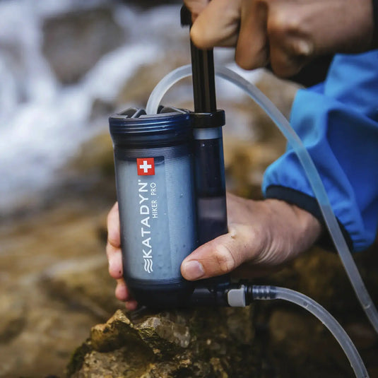 Eine Person, die einen tragbaren Wasserfilter Katadyn® Hiker Pro Wasserfilter verwendet, um Wasser aus einer natürlichen Quelle zu reinigen.