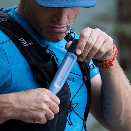 Mann mit einem Trinkrucksack, der aus einem tragbaren LifeStraw® Peak Series Straw-Wasserfilter trinkt.