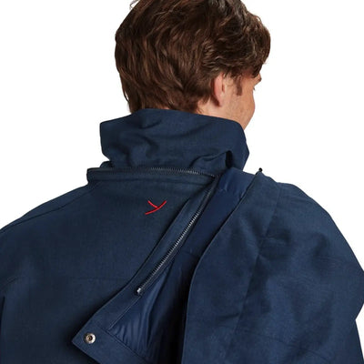 Ein Mann von hinten gesehen, der eine dunkelblaue Y by Nordisk® Marton - Herren Hardshell Daunenjacke mit einem roten Emblem am Kragen trägt.