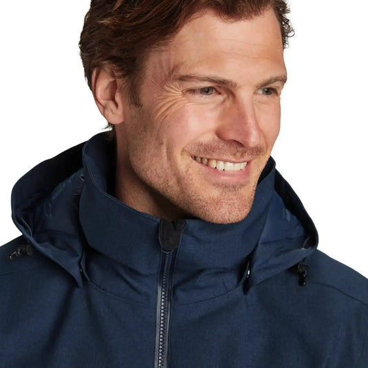 Mann lächelt und trägt eine dunkelblaue Y by Nordisk® Marton - Herren Hardshell Daunenjacke mit hohem Kragen.