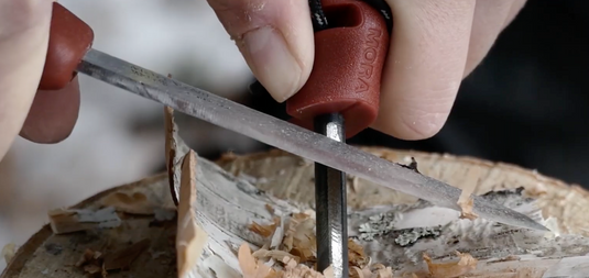 Hände feilen einen Nagel in Holz, Handwerk, Präzisionsarbeit, Werkzeugnutzung.