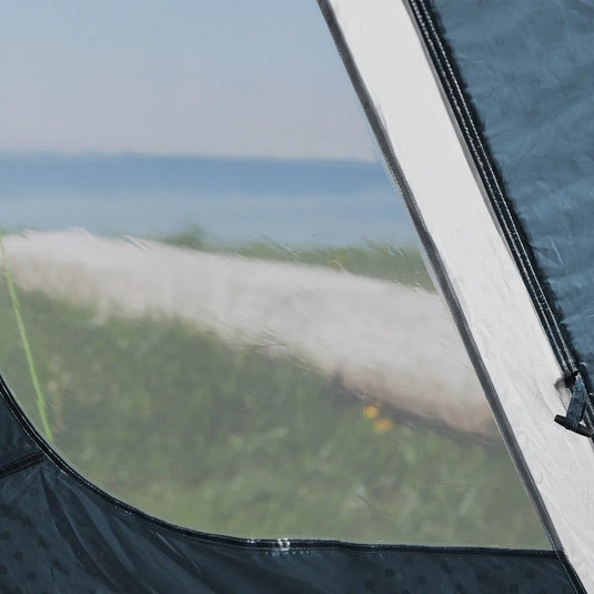 Blick auf einen Strand durch das Fenster eines Outwell® 5-Personen-Zelts – Cloud 5 Plus auf einem Campingausflug.