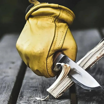 Ein abgenutzter Lederhandschuh ergreift ein ØYO Rondane Slirekniv und spaltet ein kleines Stück Holz.