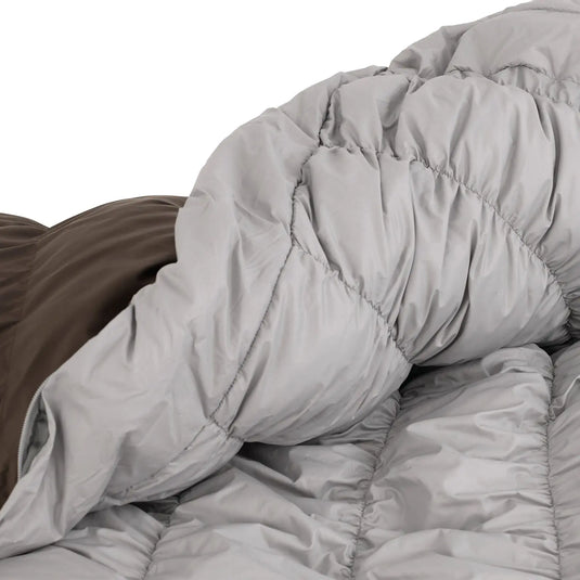 Eine Nahaufnahme einer grau gesteppten Robens® Schlafsack Serac 300 -4°C Bettdecke auf einem Bett.