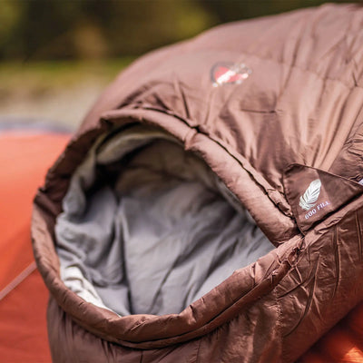 Nahaufnahme eines Robens® Schlafsack Serac 300 -4°C-Schlafsacks mit der Aufschrift „600 Fill“, positioniert neben einem Robens-Campingzelt.