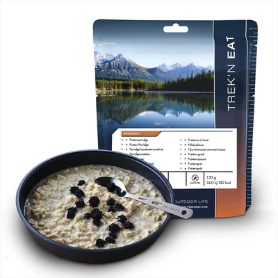 Abgepackte Outdoor-Mahlzeit von Trek'n Eat Protein Porridge mit Beeren in einer Schüssel neben der Verpackung.