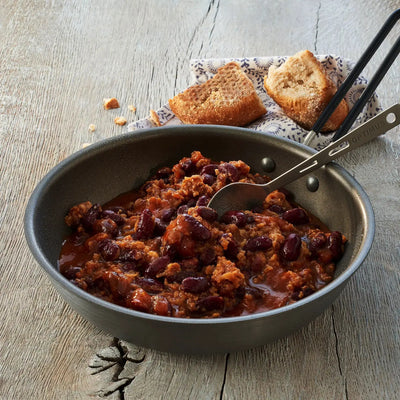 Eine Pfanne mit Trek'n Eat Chili con Carne und einer Beilage Brotscheiben.