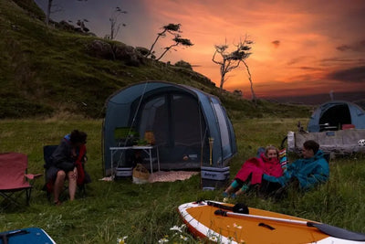 Camper entspannen sich in der Abenddämmerung mit Kajaks in der Nähe ihres Vango™ „Harris 350“ Tunnelzeltes.